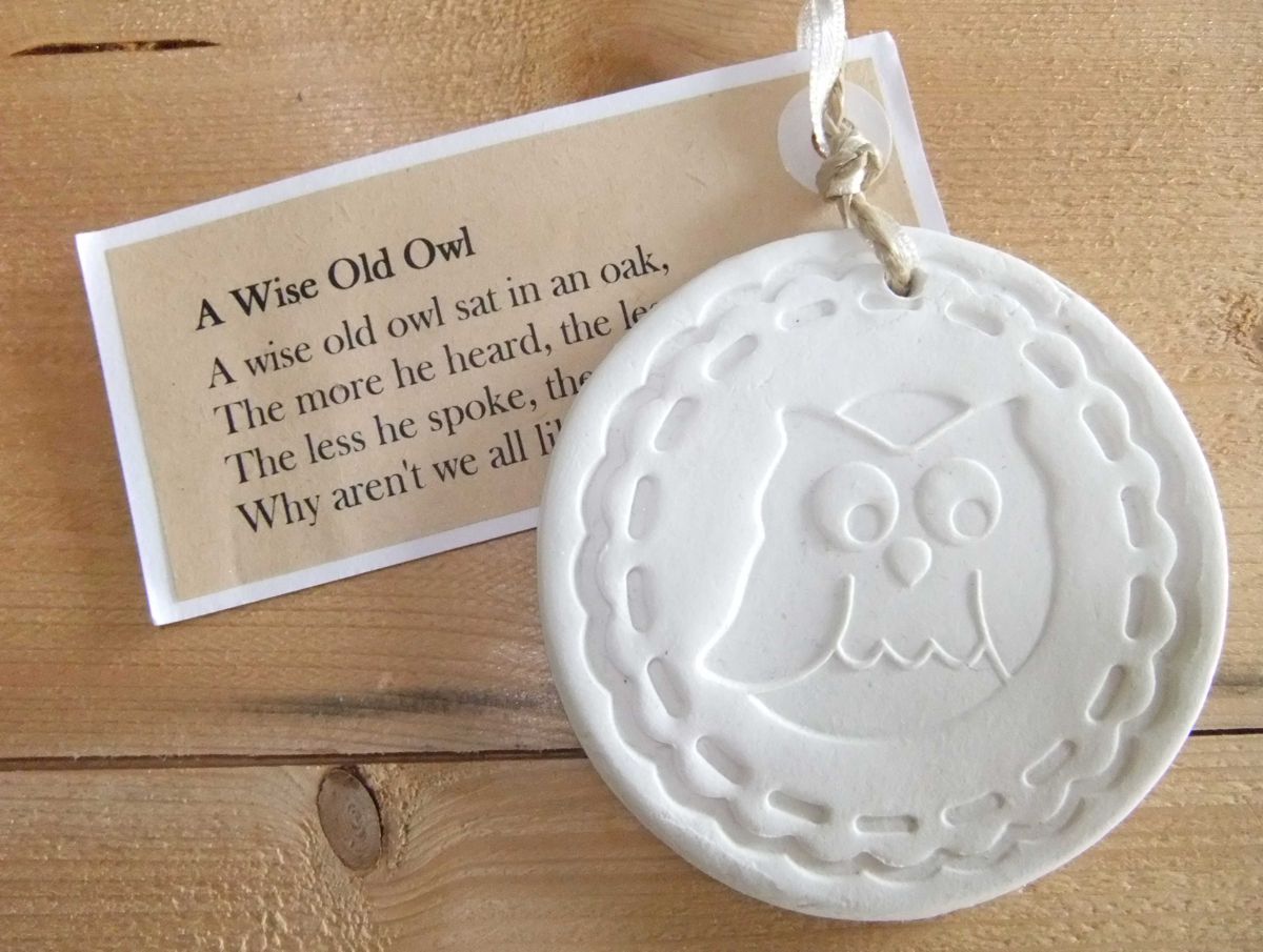 Eine runde weiße Tonscheibe mit Eulen-Stempelabdruck und Text-Anhänger 'A wise old owl...'