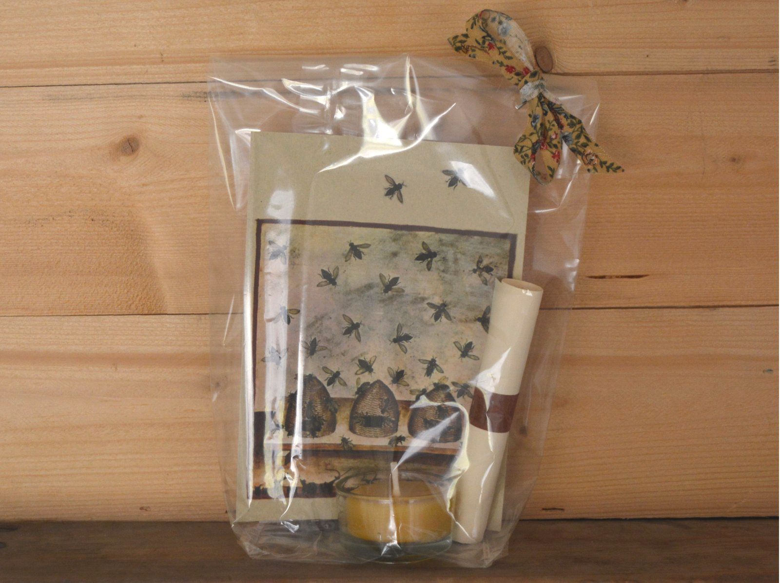 Geschenkig verpackte Postkarte mit Bienenstock aus einem antiken Buch, dazu ein Bienenwachs-Teelicht, Blütensamen-Päckchen und ein Blatt mit dem Spruch.